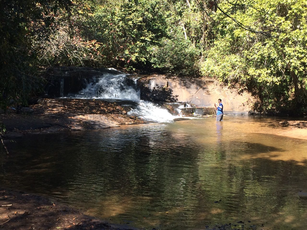 Cachoeira em meio à mata com pessoa na água